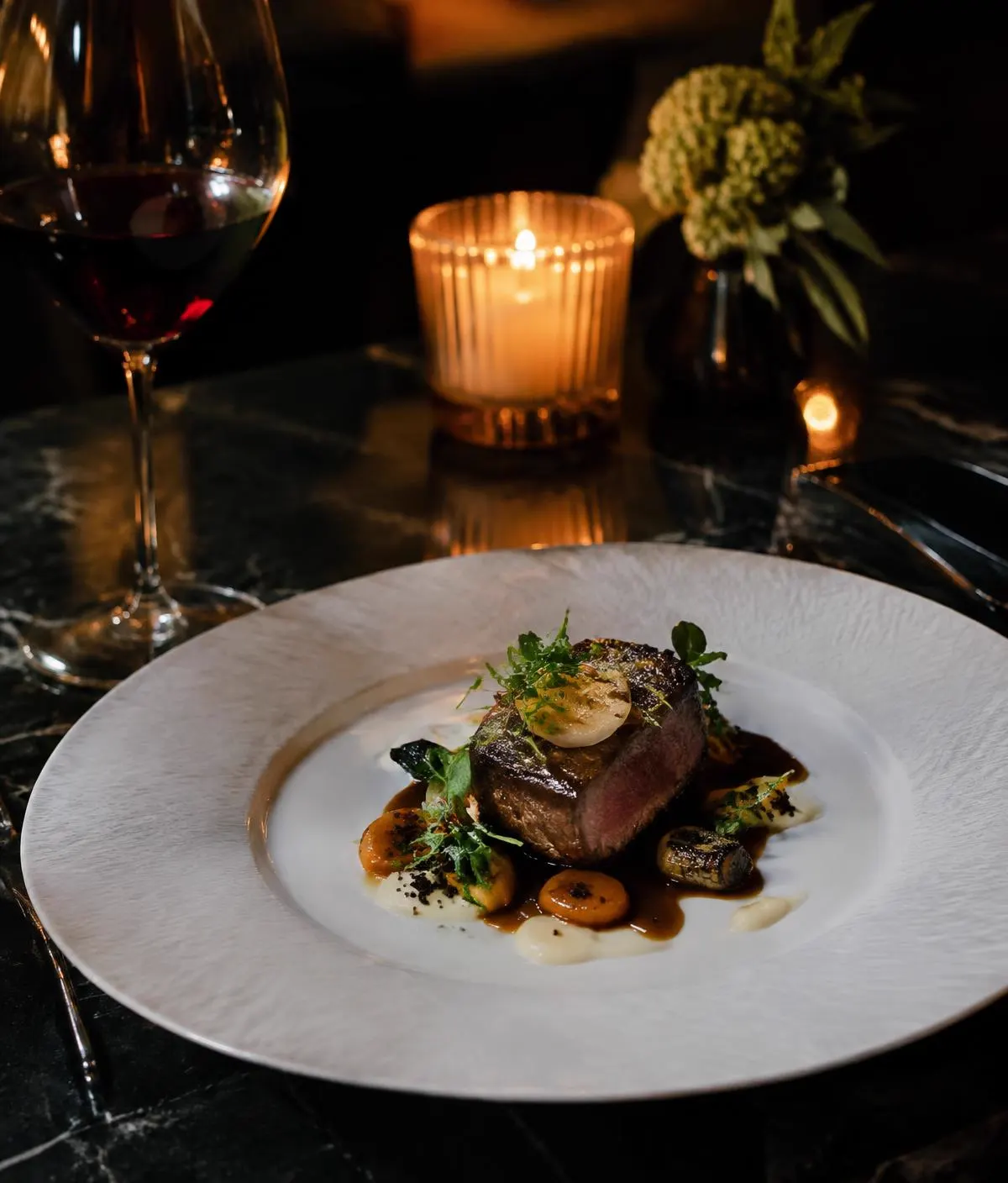Prato de alta gastronomia servido à luz de velas em restaurante de hotel